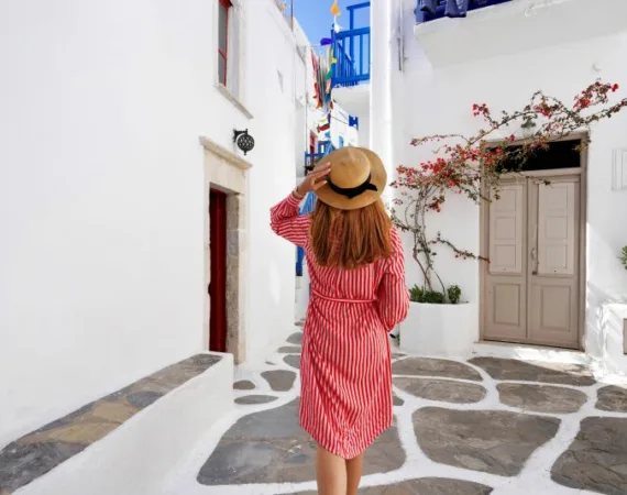 Tourist woman walks through the alleys in Mykonos picturesque town in Greece